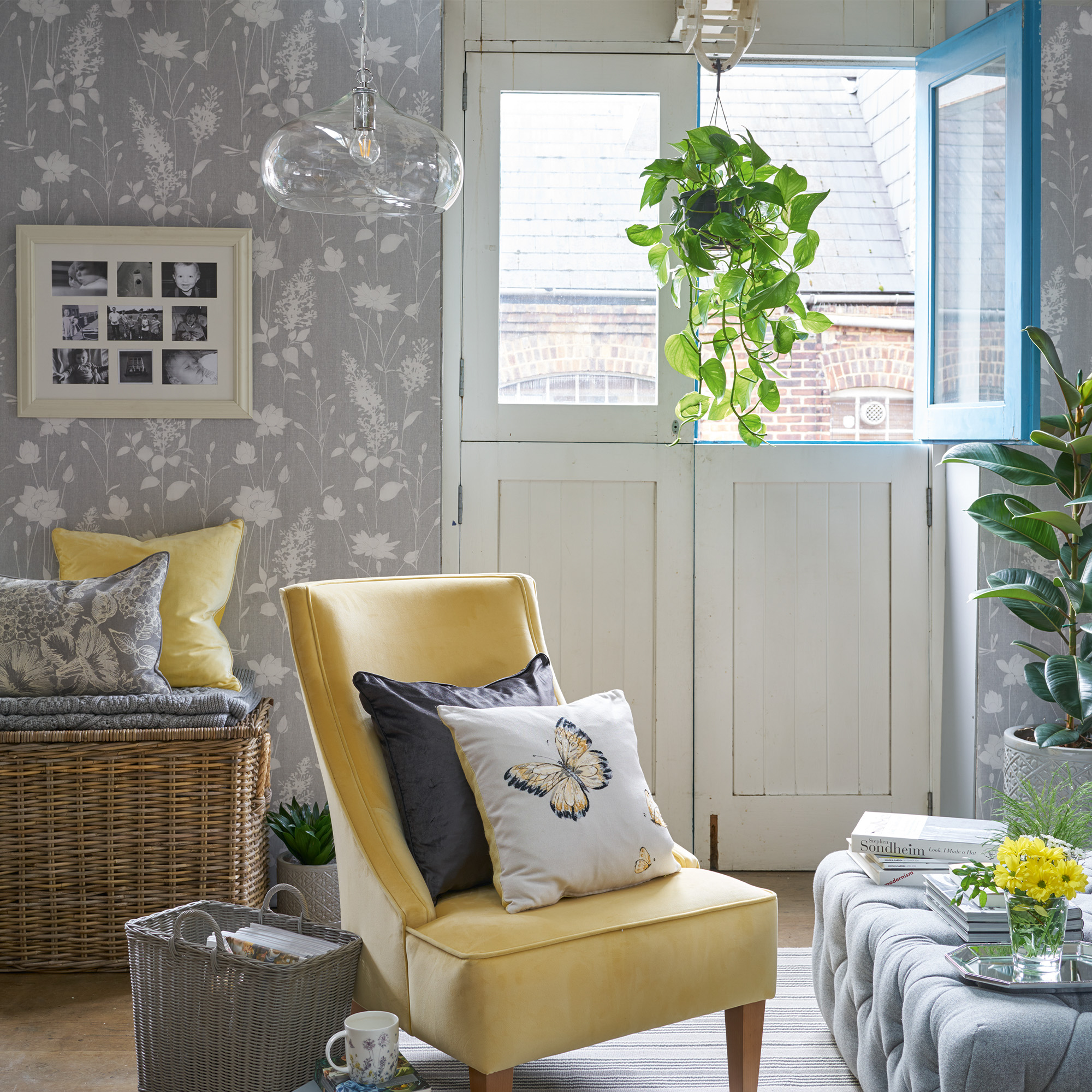 Bright yellow chair placed in a room with Laura Ashley wallpaper and home accessories.