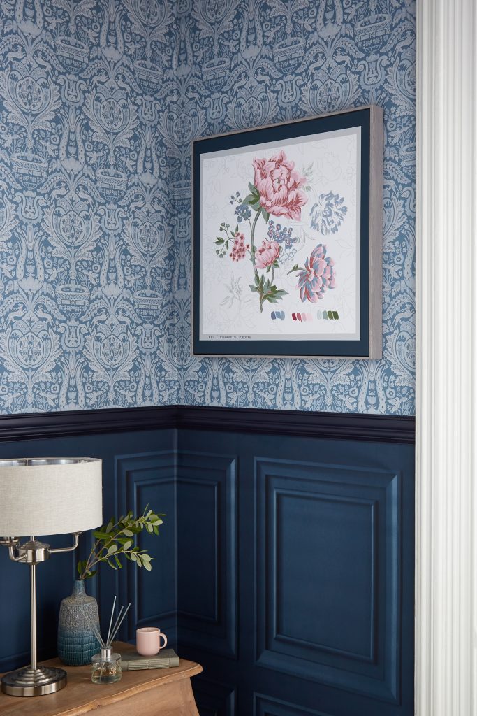 Floral tapestry wall art by Laura Ashley on a blue patterned wall paper.