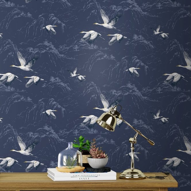 Laura Ashley Animalia wallpaper behind a desk with books, plants and a table lamp.