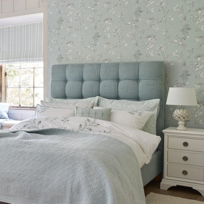 Laura Ashley wallpaper hung in a bedroom behind the bed 