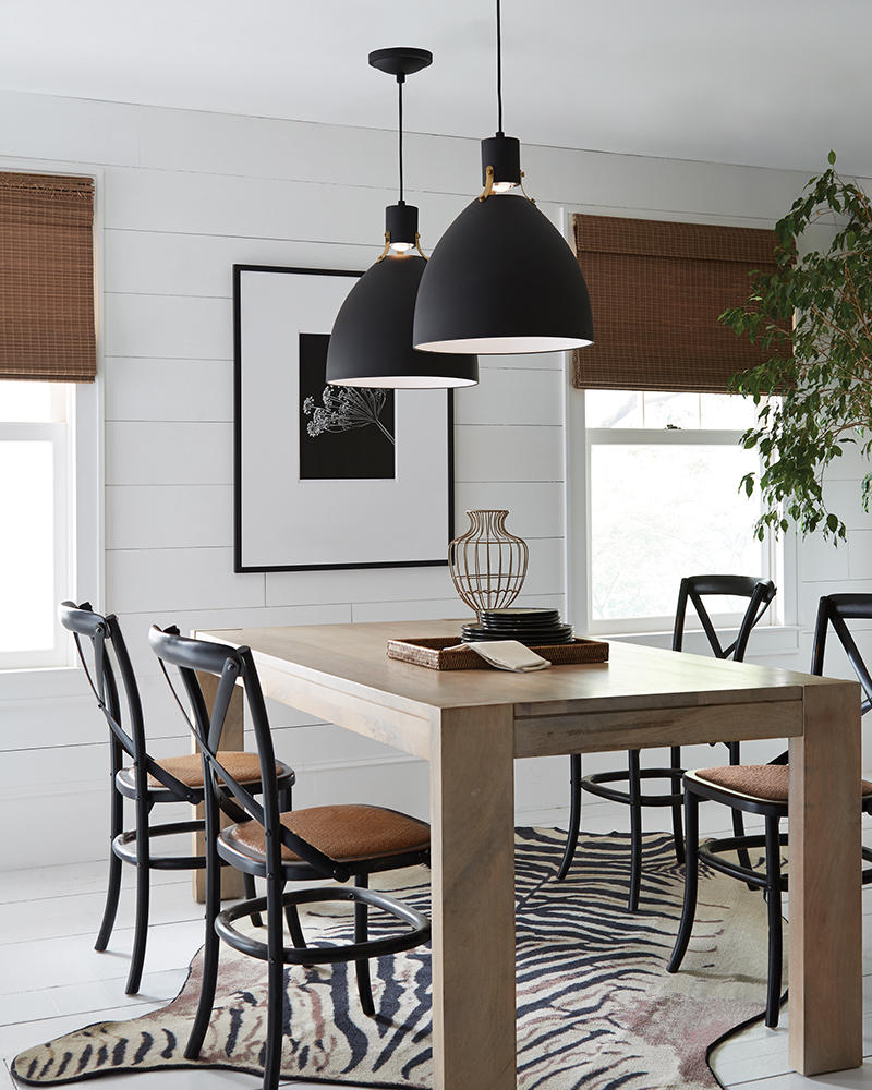 Two black pendant lights over a dining table.