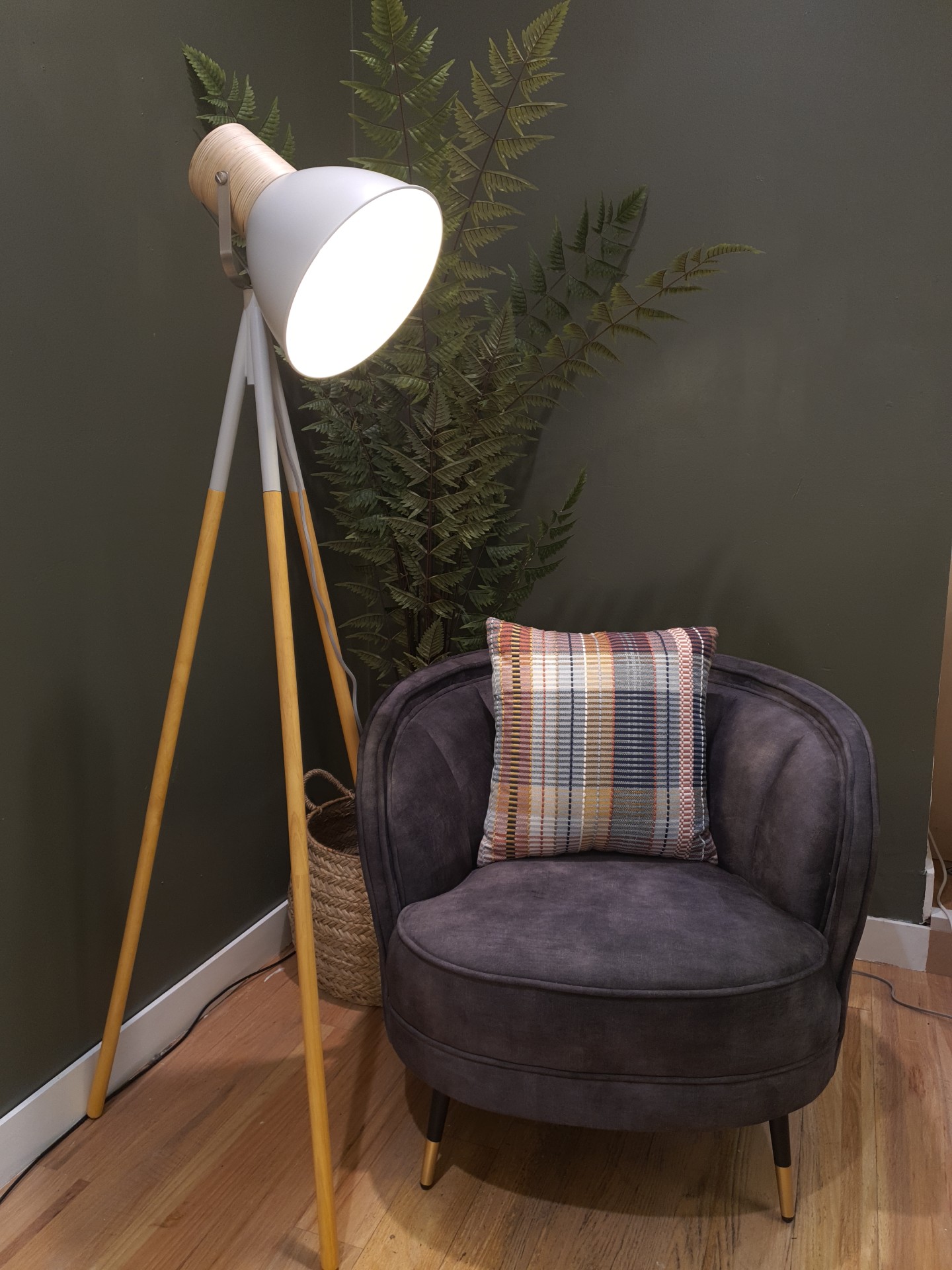 Floor lamp placed next to an arm chair with a house plant behind.