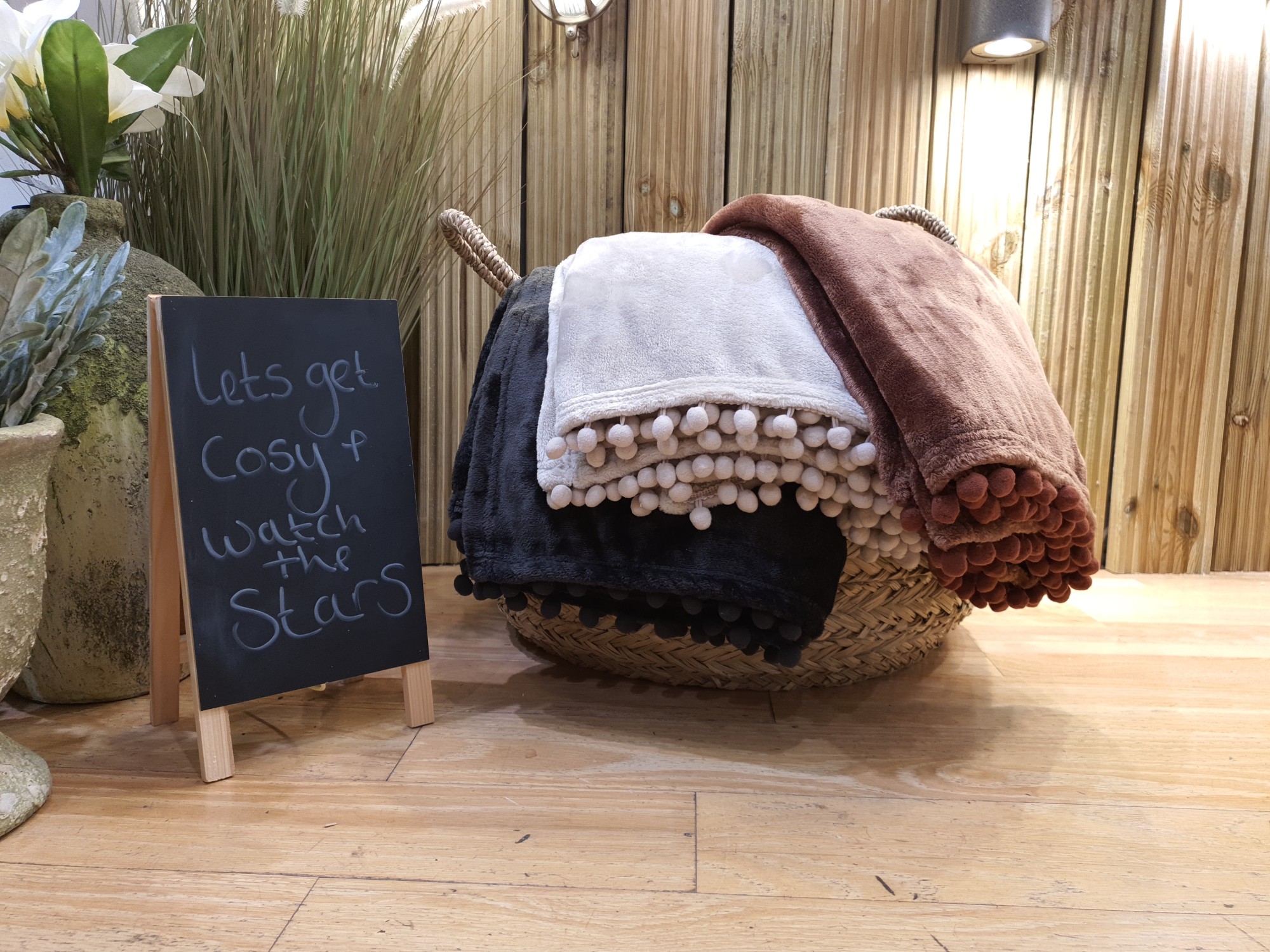 A collection of throws with a sign that says lets get cosy & watch the stars. 