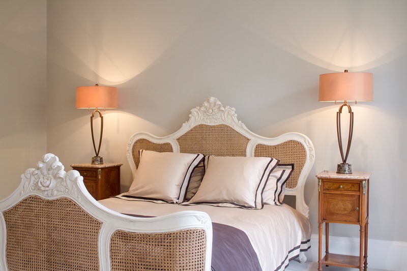 A bedroom with a table lamp either side of the bed.
