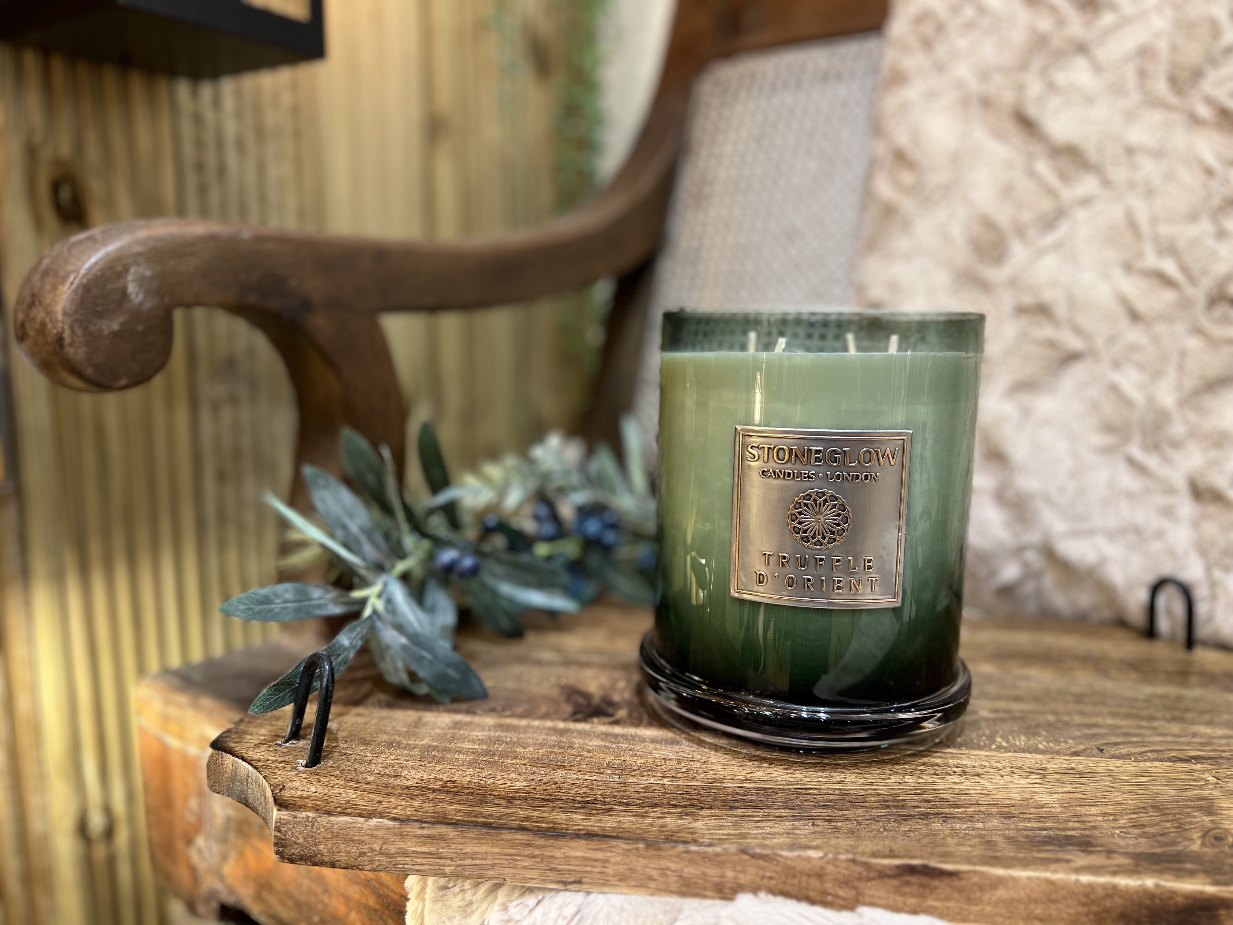 A green candle placed on an armchair with a green plant running along the side of the candle.