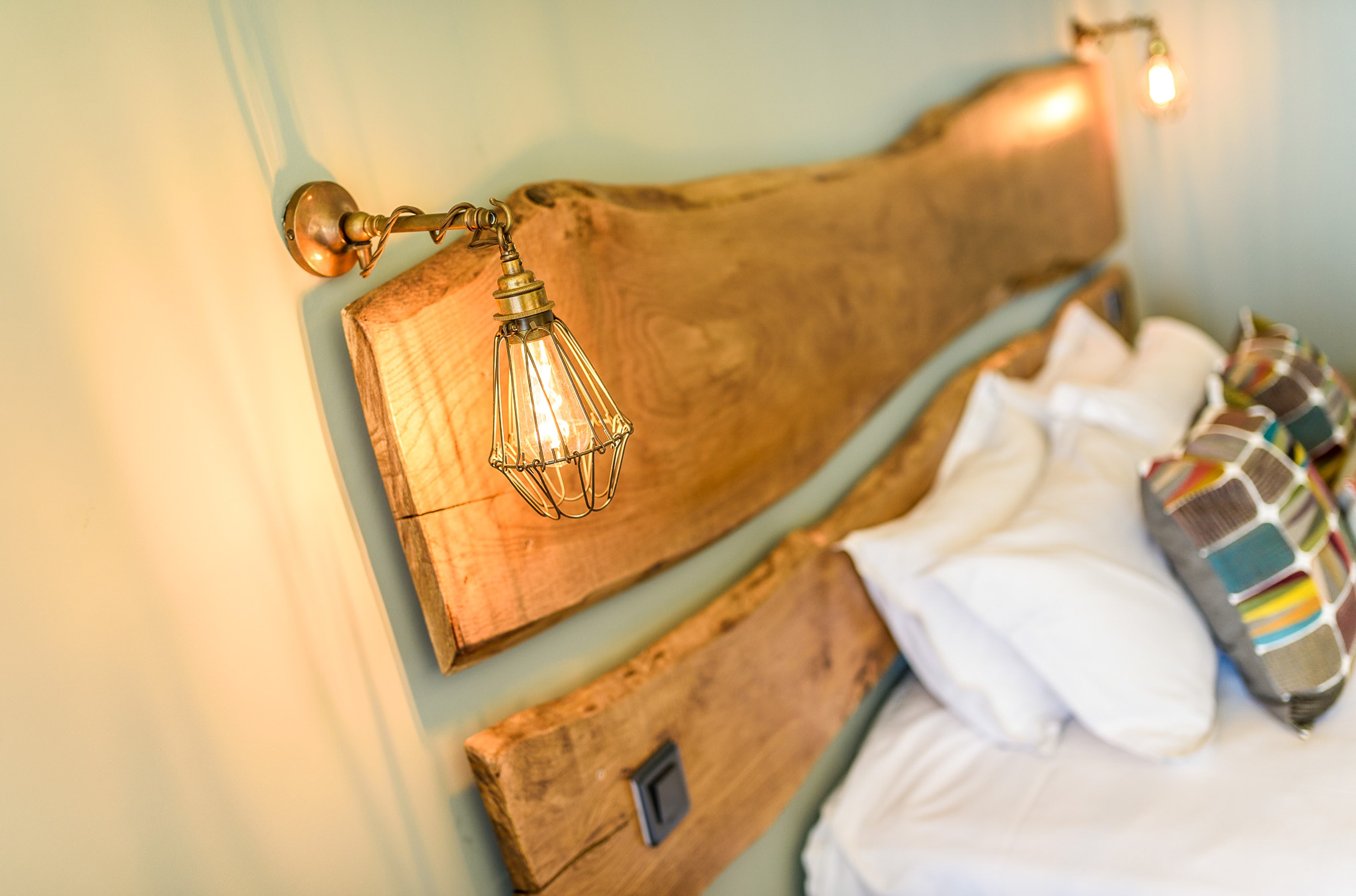 Two matching wall lights either side of a wooden panelled head board.