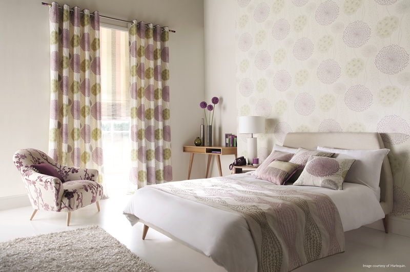 A bedroom setting with an arm chair in the corner and desk in the other corner.