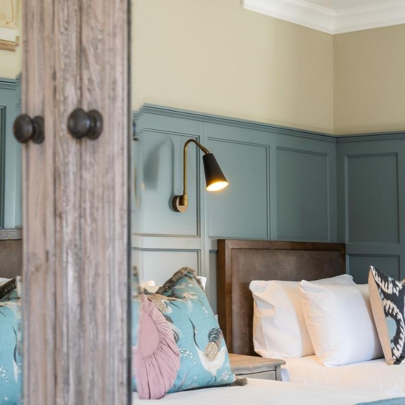 A wall light above a bed on a panelled wall.