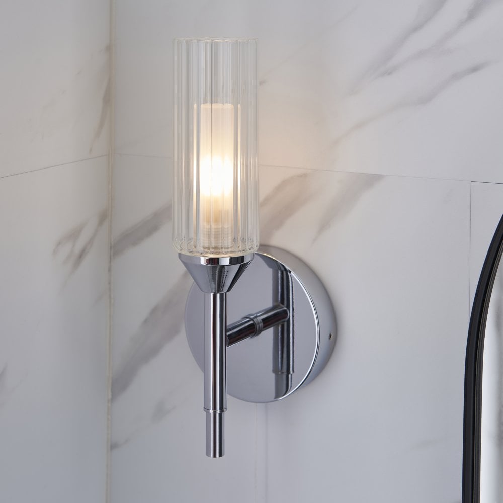 A chrome finish wall light on a marbled effect wall.