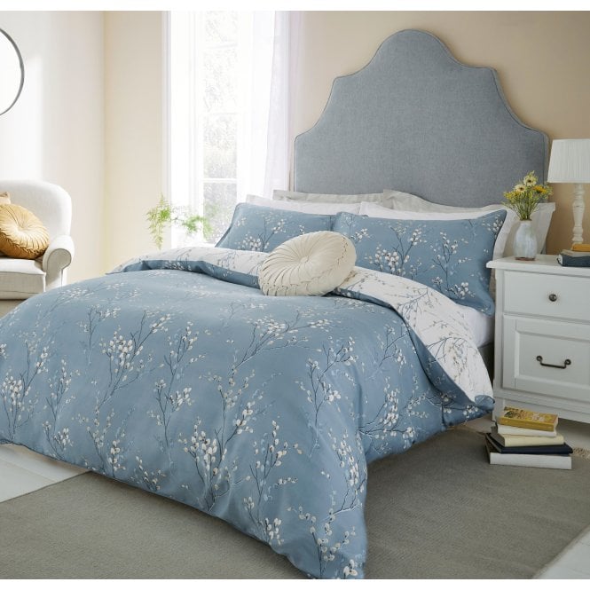 Laura Ashley bedding in a bedroom setting with a nightstand and armchair.