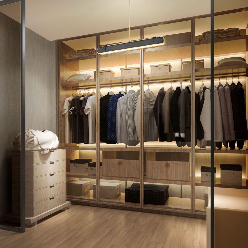 a masculine and warmly lit open wardrobe space featuring integrated strip lighting and hanging, linear pendant light fitting