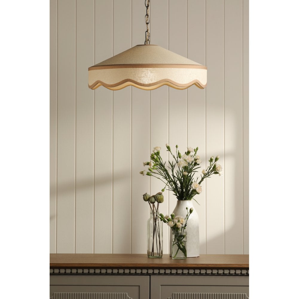 A decorative, cream and gold hanging light pendant hanging over a wooden side board with flowers