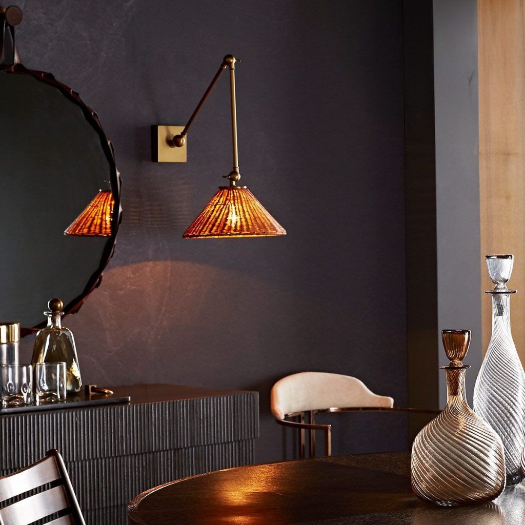 rattan Wall light shown above a side board in a moody dark room.
