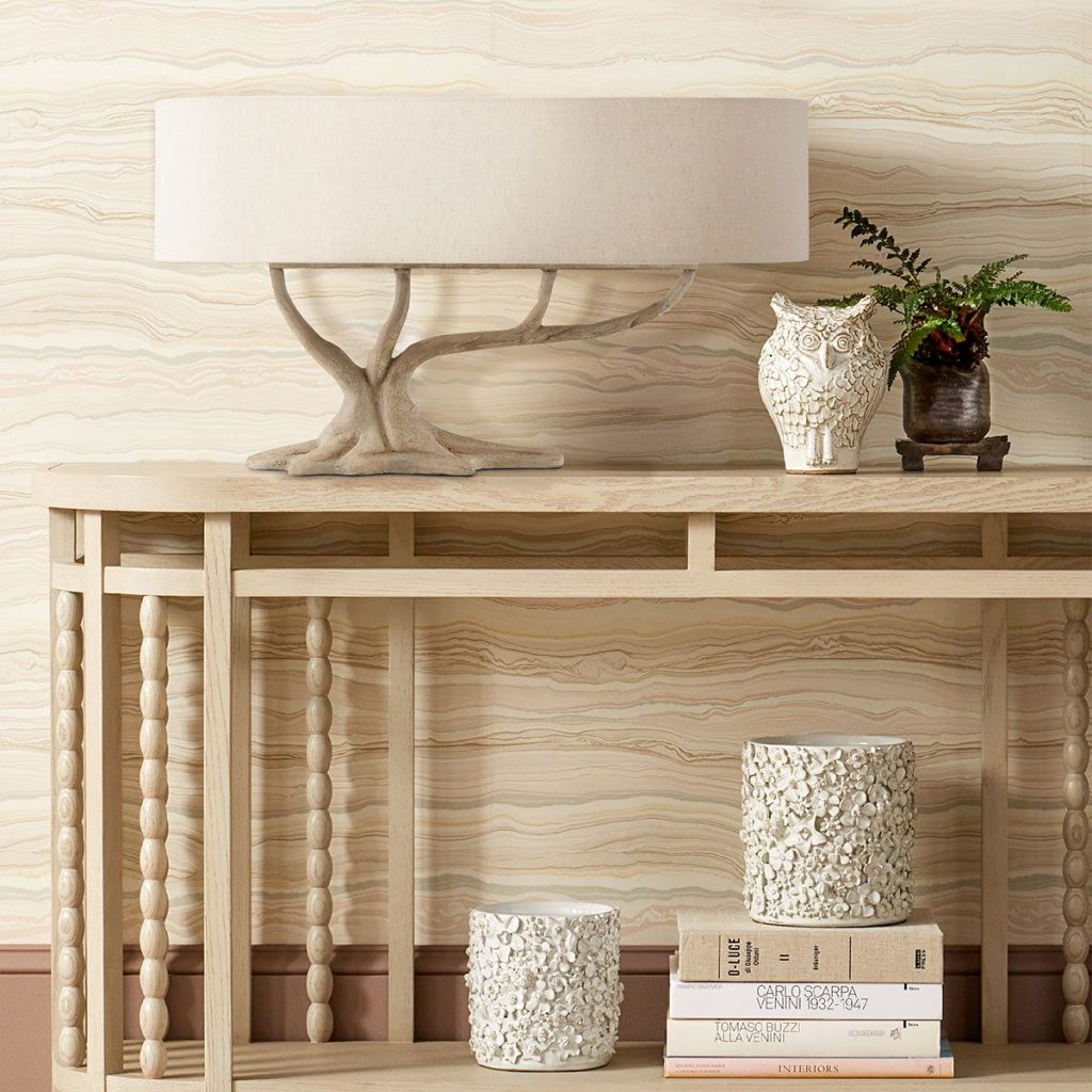 table lamp with tree effect lamp base and large oval shade on top of a rustic console table.