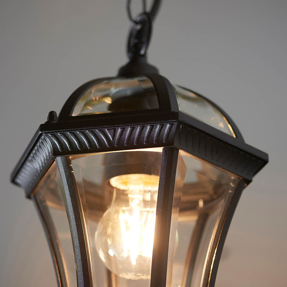 A modern wall mounted light fitting that encapsulates a warm, gothic feel with black metal frame and amber bulb