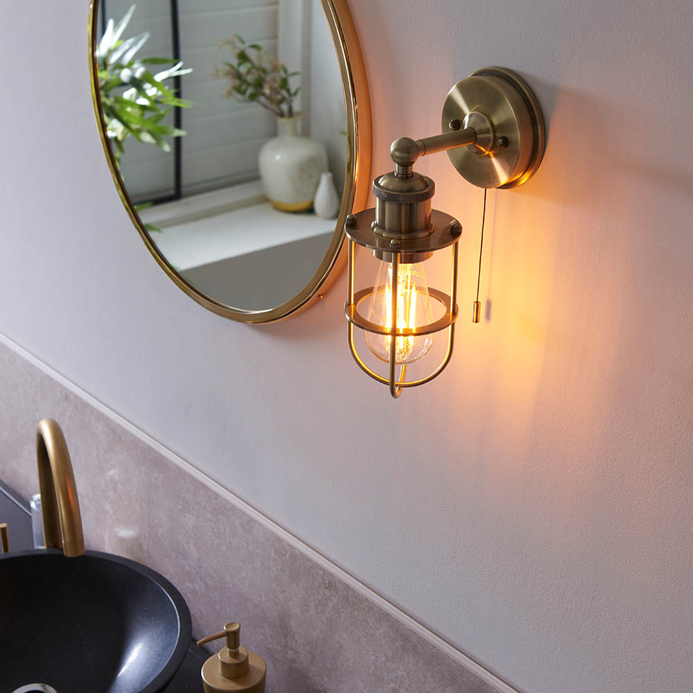 an aged brass vintage style wall light next to a mirror