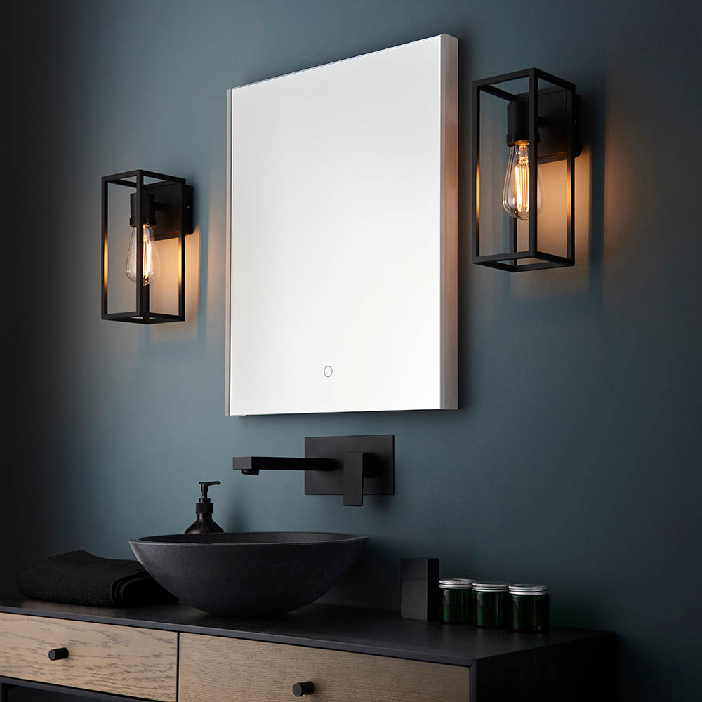 A pair of modern wall mounted light fittings that encapsulates a warm, gothic feel with black metal frame and amber bulb fitted either side of a bathroom mirror