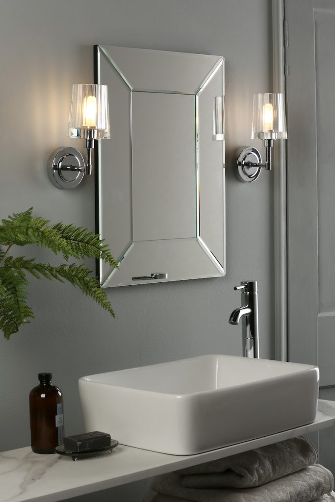 a modern bathroom featuring victorian inspired wall lights either side a mirror