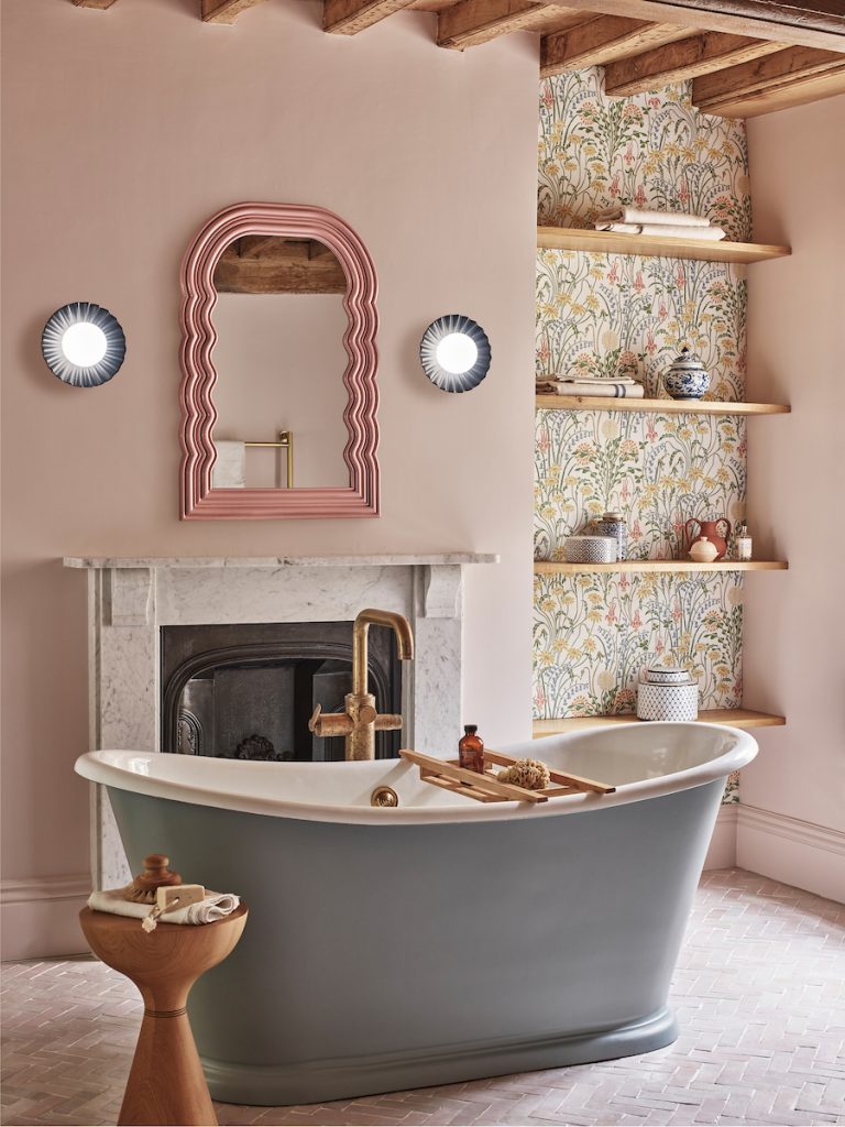 a traditional style bathroom in pink and floral finish with two wall mounted lights beside a mirror