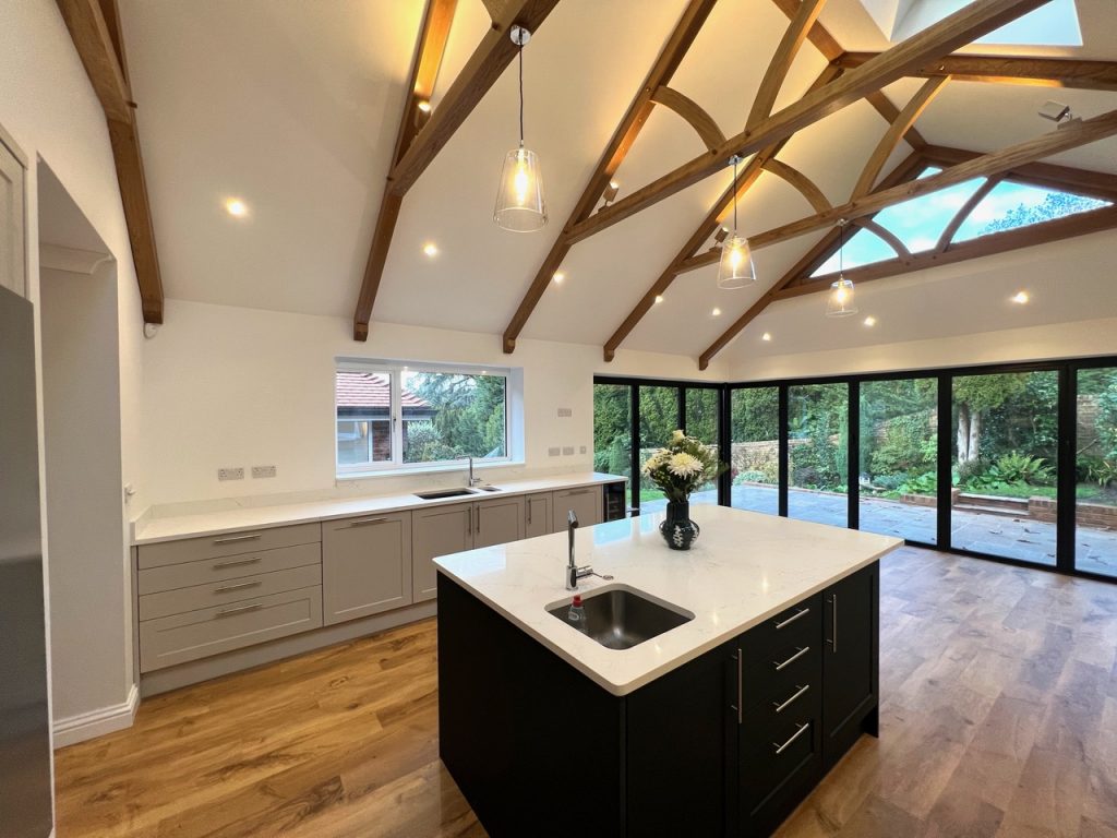 a large kitchen with open vaulted ceilings and beams with spotlights and pendant lights