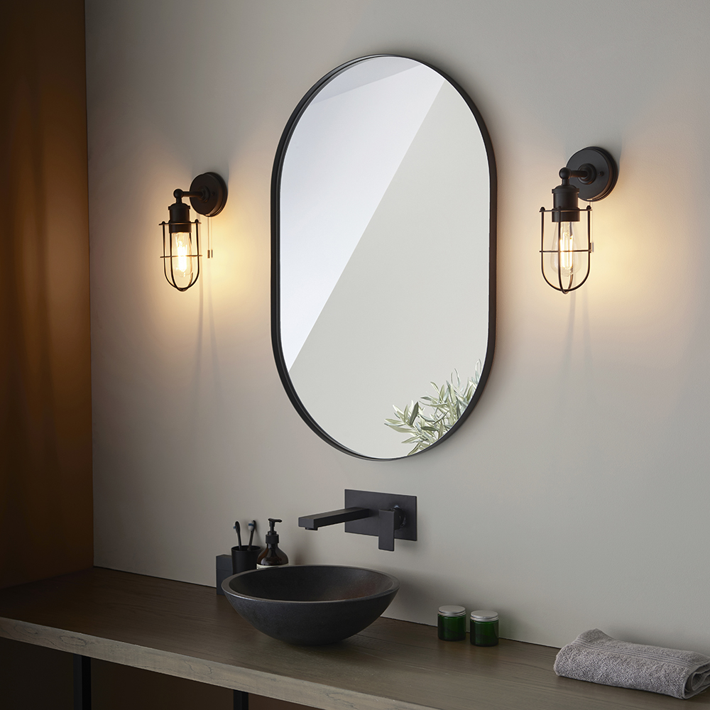 A pair of black wall mounted light fittings in a modern gothic style with warm LED bulbs suited to a period home