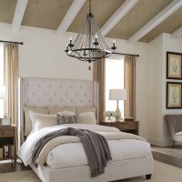 a black chandelier with candle effect bulbs in a gothic or medieval style hanging in a bedroom