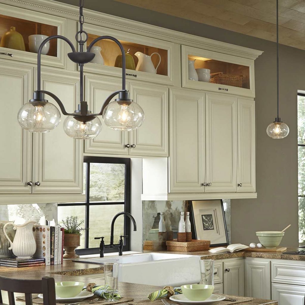 a black, chain hung, celling chandelier with warm bulbs and clear glass shades in a kitchen