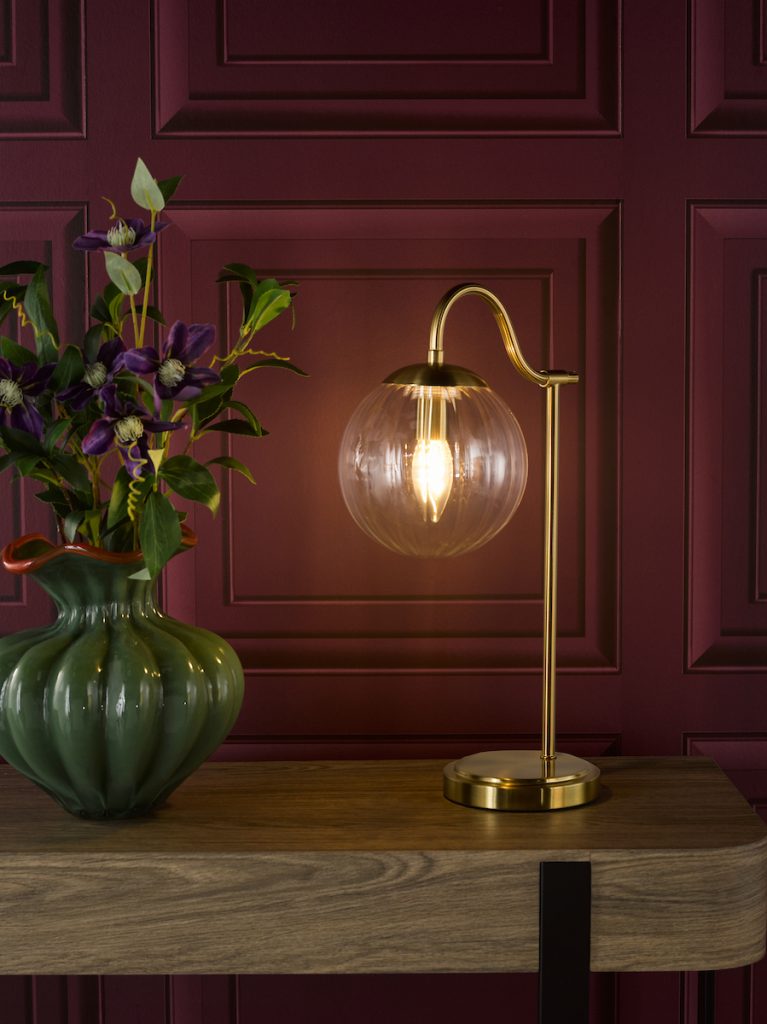 an antique brass table lamp with glass shade on a side table