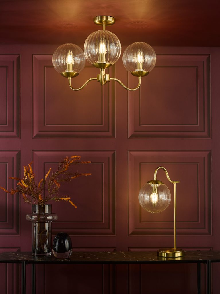 brass and glass semi flush ceiling light and matching table light on a sideboard