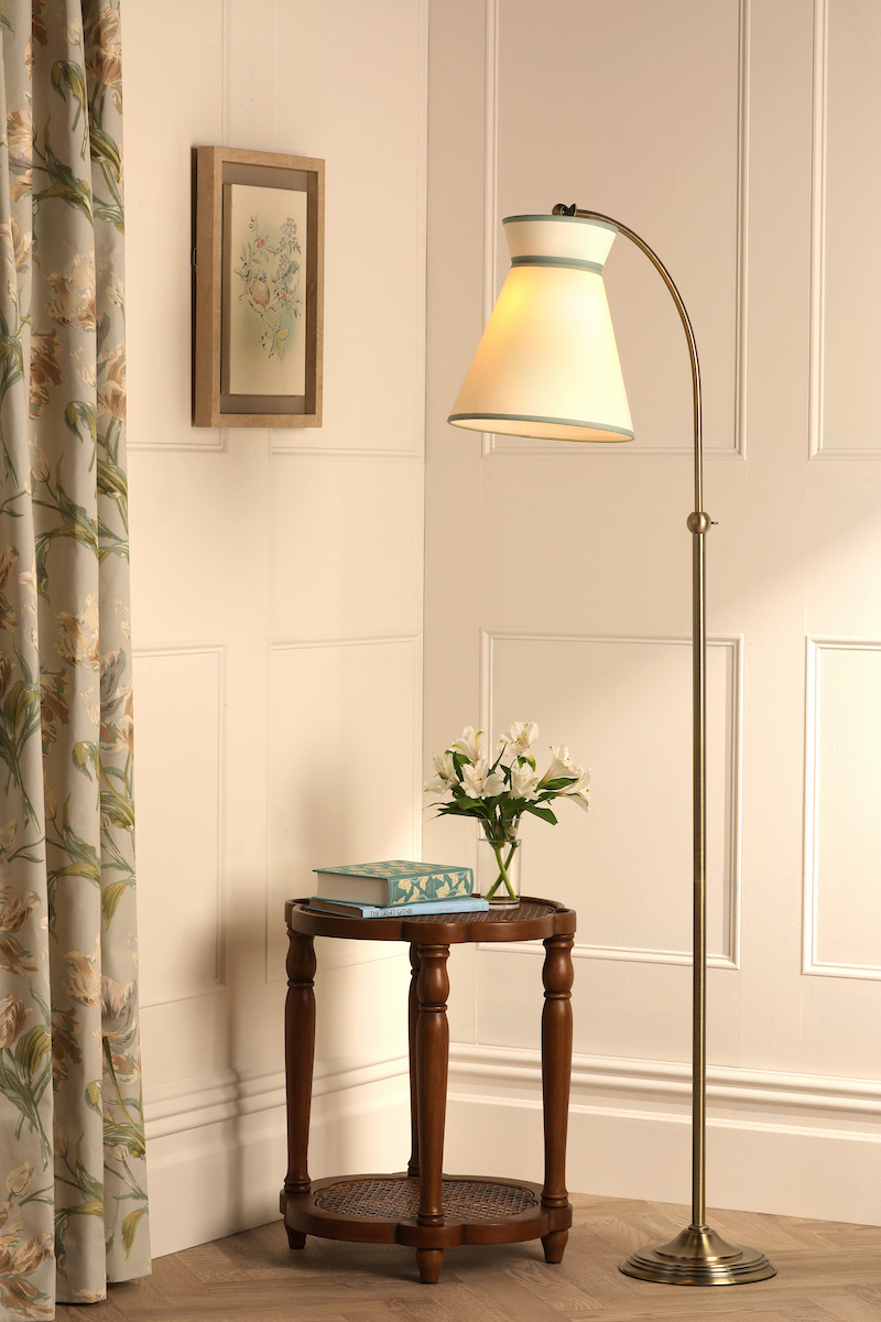 a large cream lined and brass floor lamp and small side table