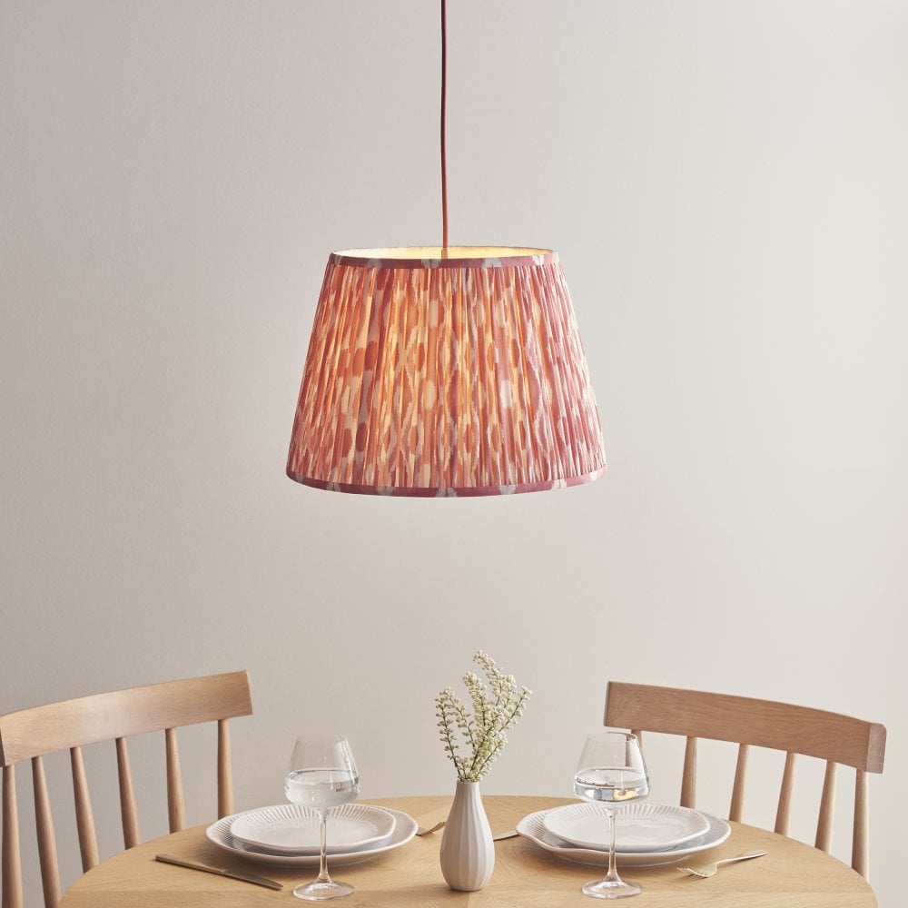 a pink patterned fabric lightshade suspended over a dining tabe