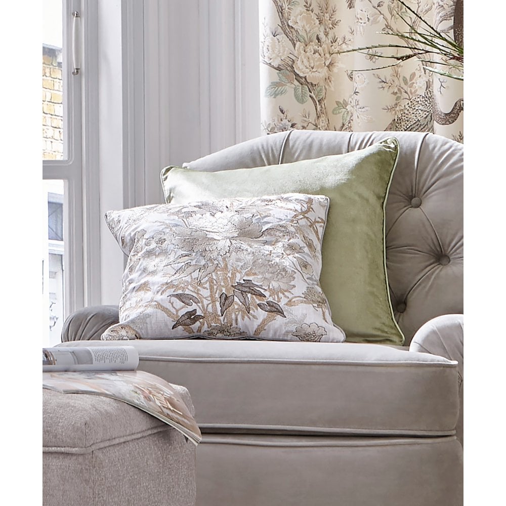 patterned cushion and green cushion on a grey armchair in a living room