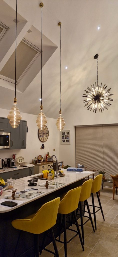 a large modern kitchen with pitched ceiling and statement lights pendants