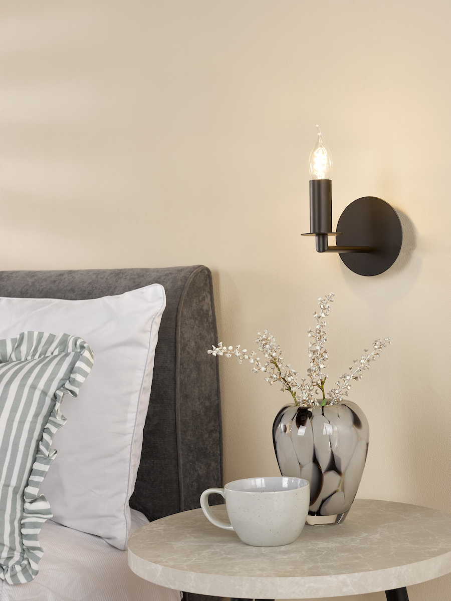 a matt black wall sconce with exposed candle bulb with bent tip.