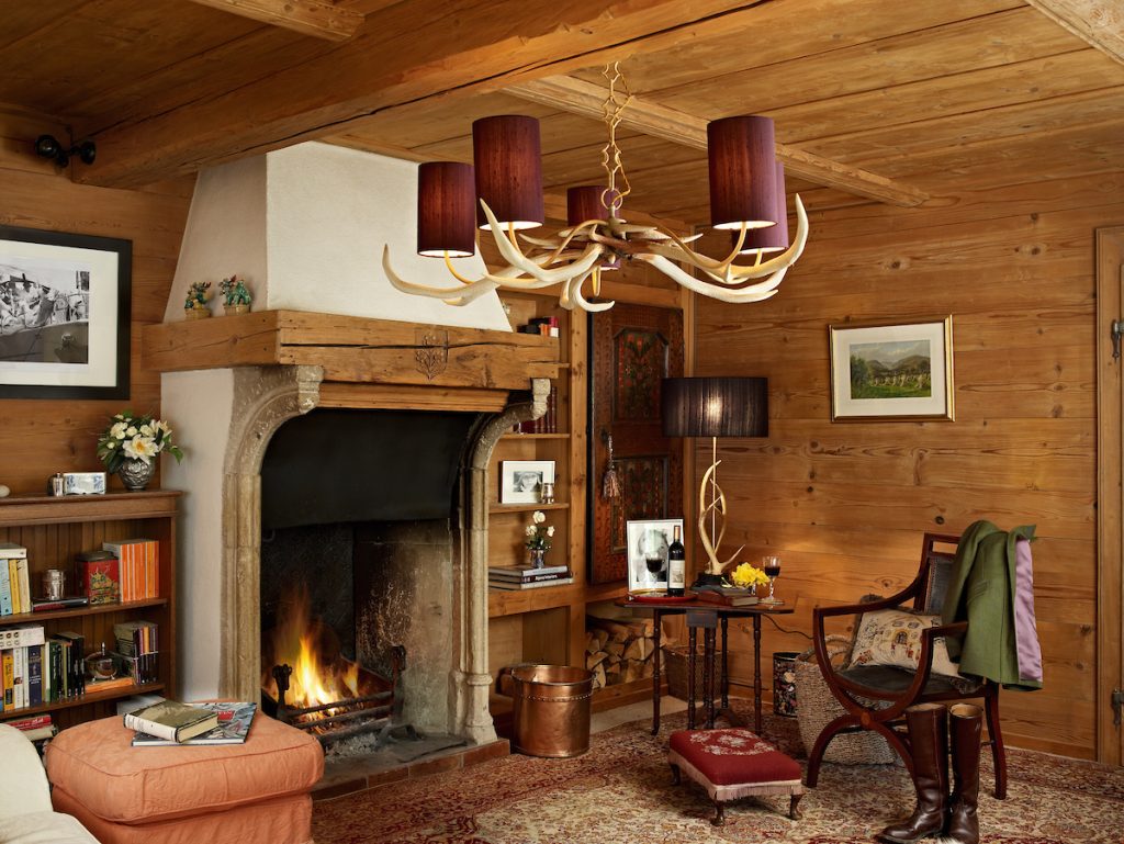 a log cabin inspired living room with stone fireplace and antler pendant light and table lamp with purple shades