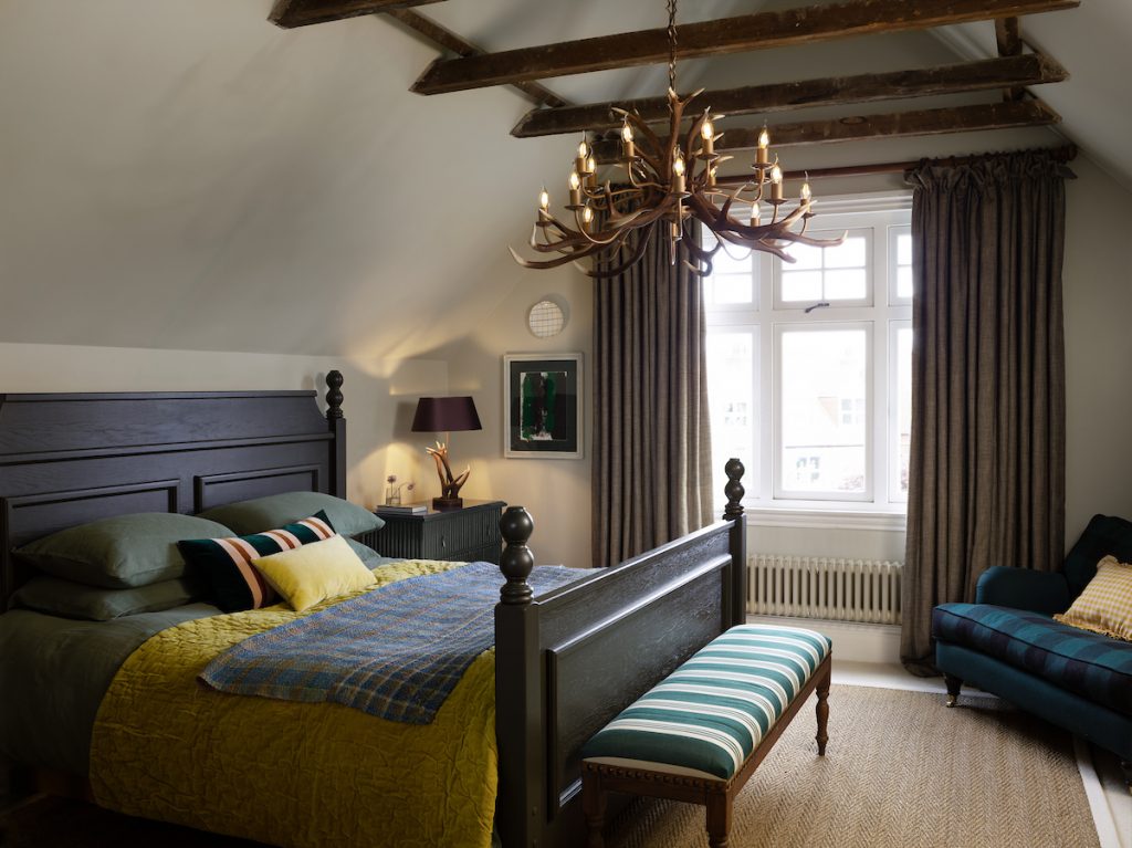 a high ceiling bedroom with a large statement antler chandelier