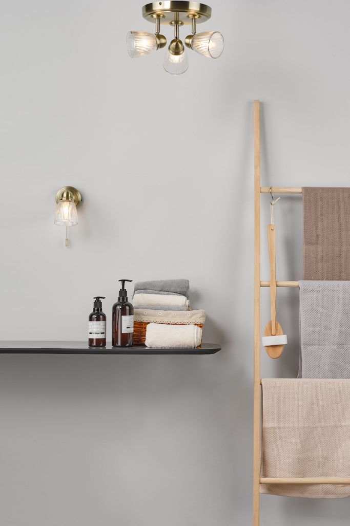 a matching brass and ribbed glass wall light and semi flush ceiling light in a bathroom