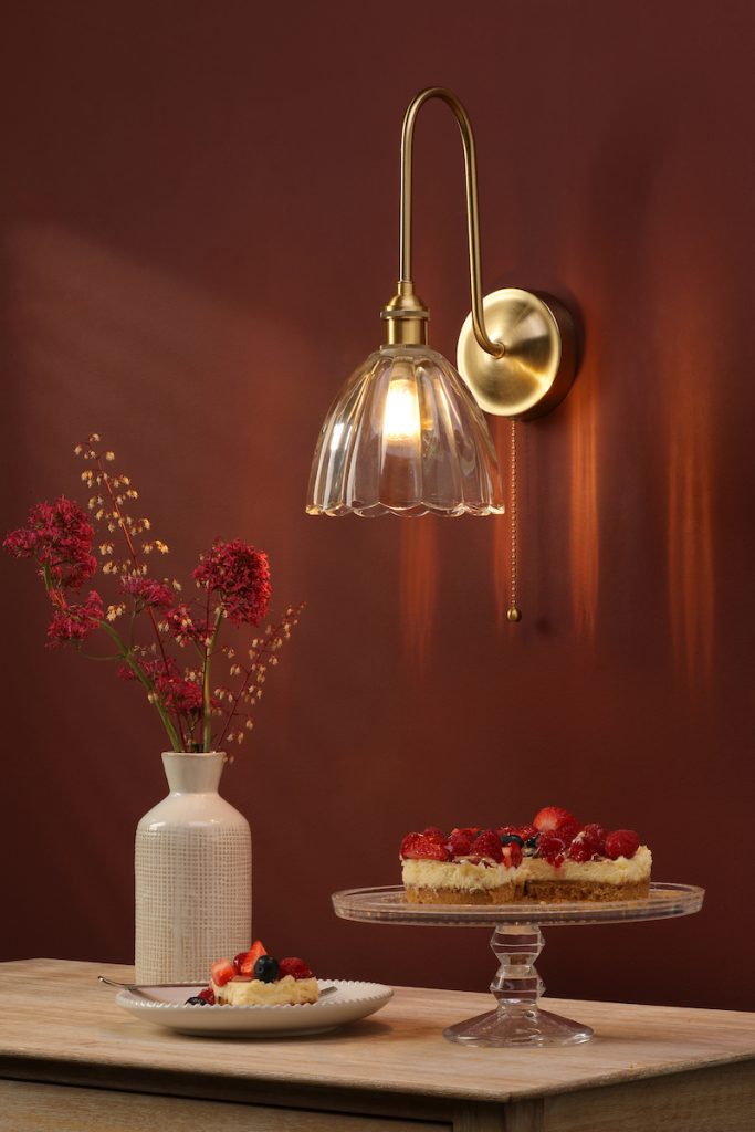 a vintage, aged brass wall light with scalloped glass shade
