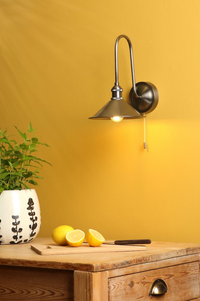 an aged brass wall light with brass shade