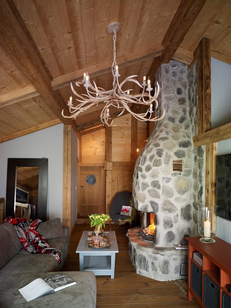 a large antler style pendant hanging from a sloped ceiling in s lodge style living room