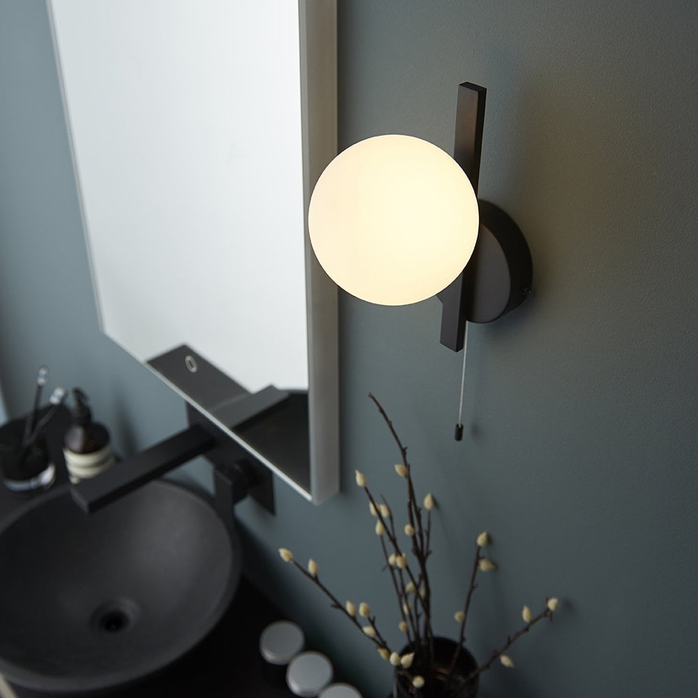 a modern bathroom wall light with black mount and opal glass shade
