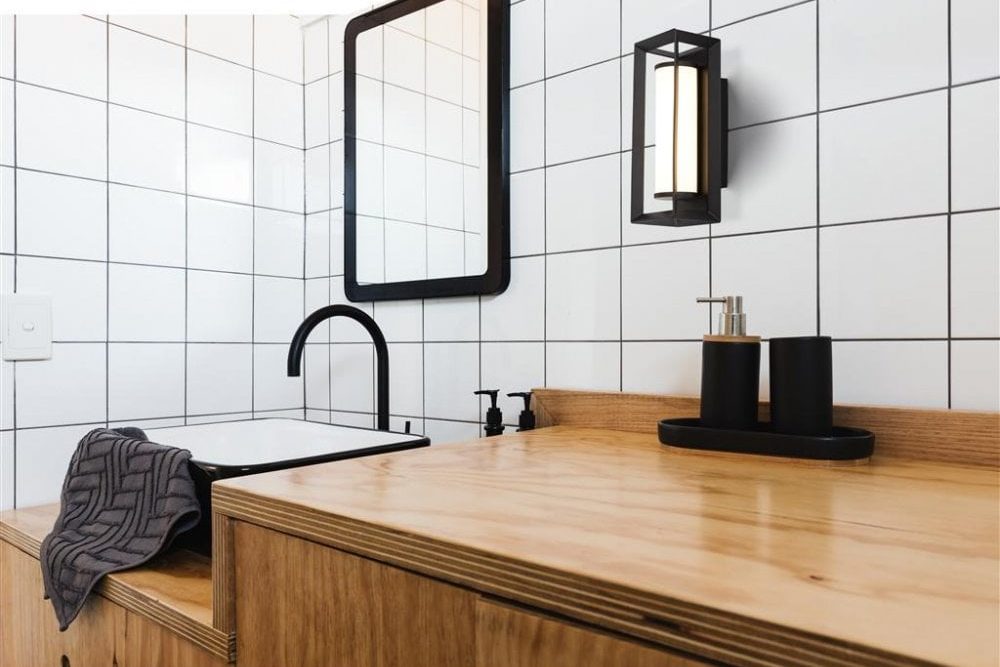 modern black and glass bathroom wall light next to a matching mirror