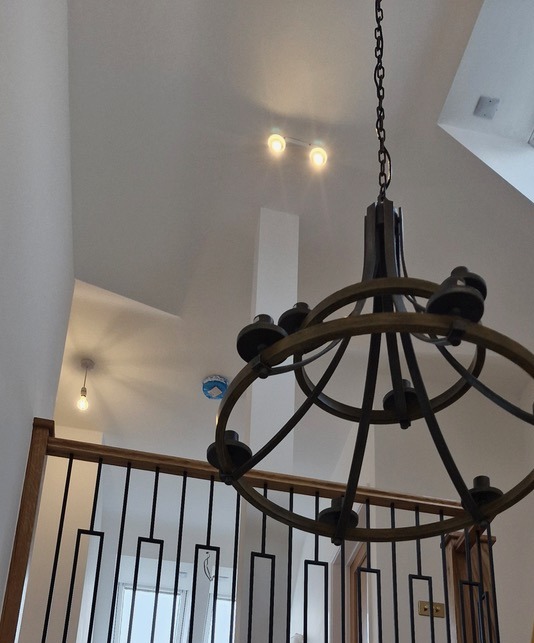 a tall stairwell with large hanging pendant light and surface mounted spot lights