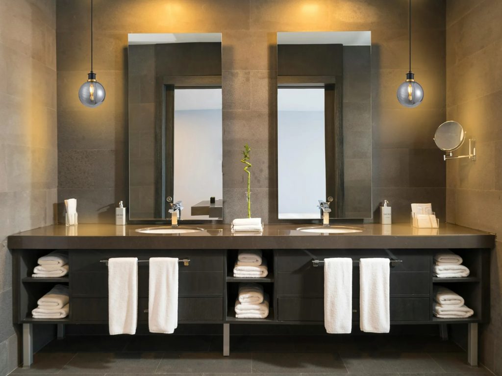 modern spa like bathroom with recessed spot lights and pendant lights beside a double vanity unit
