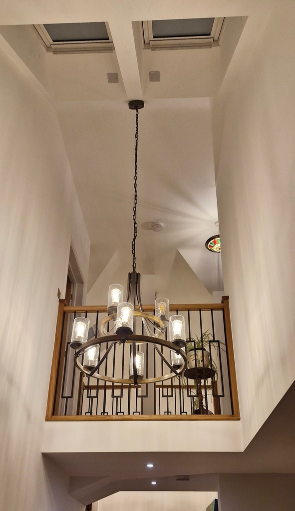 A tall hallway with sloped ceiling and skylights with a large statement pendant light
