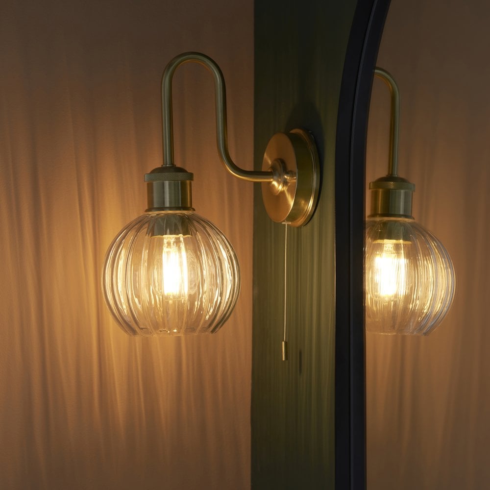a heritage brass wall light fitting with a segment glass shade typical of the Victorian era