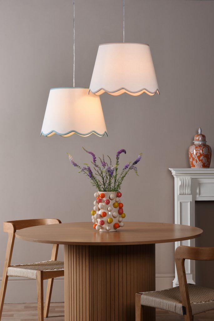 two neutral lampshades with scallop edge detail suspended from a ceiling