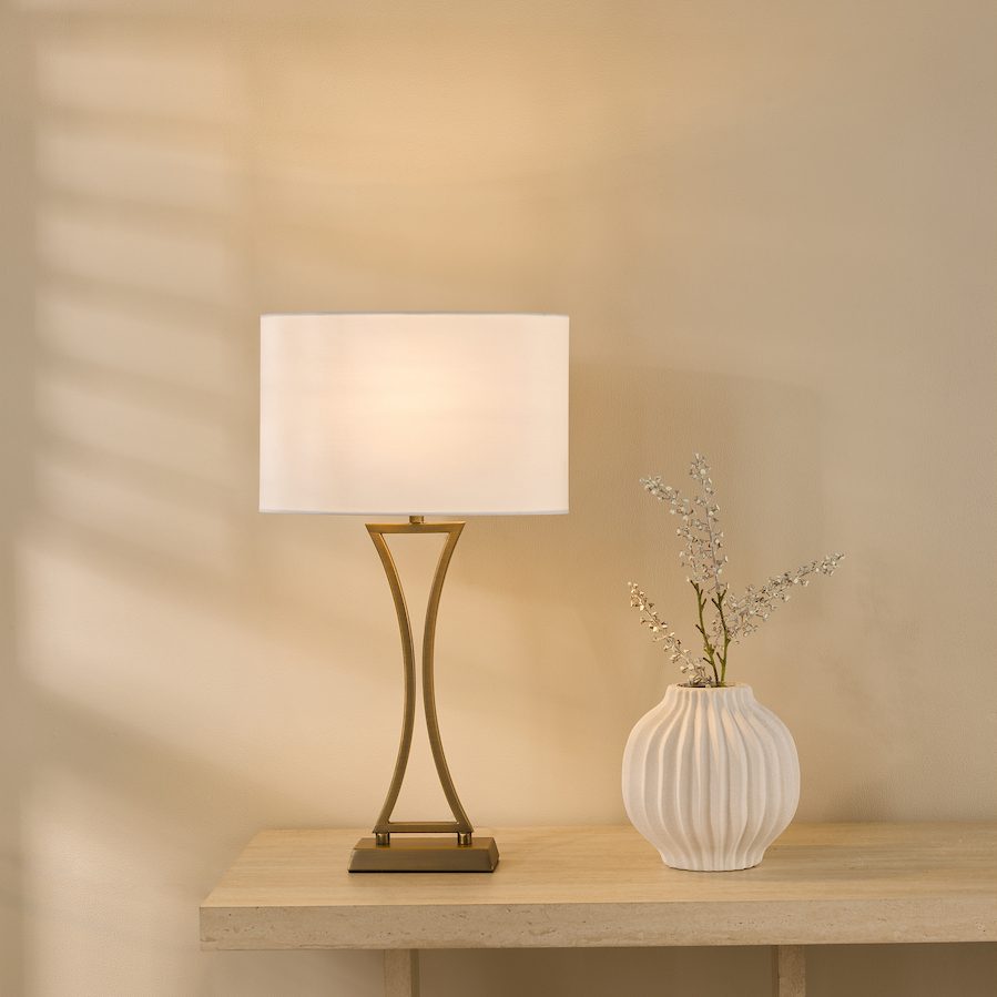 a curved metallic table lamp with oval on trend lampshade