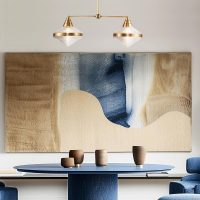Twin pendant light diffused glass and brass above a modern table blue art work.