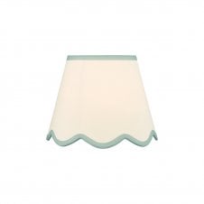 A neutral scalloped edge table lamp shade with blue accent edging